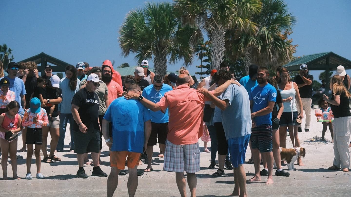 A baptism moment at Discovery Church, hands meeting in the water.